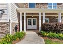 Welcoming front porch featuring stone accents, white columns, and a pathway with yellow flowers at 3415 Kenyon Creek Nw Dr, Kennesaw, GA 30152