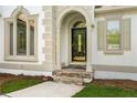 Close-up of front door with elegant stone entrance and arched window features at 7025 Bavarian Wood Pl, Buford, GA 30518