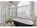 Luxurious bathroom featuring a soaking tub, a glass-enclosed shower, and an arched window at 5440 Old Haven Ct, Cumming, GA 30041