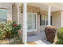 Inviting covered front porch with brick accents and decorative shrubs at 507 Vaughan Dr, Hampton, GA 30228