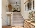 Inviting foyer features carpeted stairs, a wooden railing, and views into the open floor plan at 33 Evans Point Pt, Dallas, GA 30157