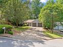 Single-story home with a two-car garage and long driveway nestled in a private, wooded setting at 10650 Colony Glen Dr, Johns Creek, GA 30022