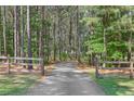 Scenic driveway leading through a lush, wooded landscape with a rustic wooden fence at 625 Henderson Mill Rd, Covington, GA 30014