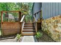 Wooden stairs leading to the home with stone accents, metal railings, and lush greenery surrounding at 945 Tiber Cir, Alpharetta, GA 30022