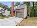 Side view of a charming home boasting an attached garage, brick chimney, and lovely yard at 1111 Pin Oak Dr, Tucker, GA 30084