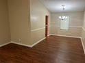 Dining room showcasing a modern chandelier, wood-look floors, and large wall trimmed in wainscoting at 6536 Rebecca Lou Ln, Lithonia, GA 30058