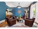 Stylish living room boasts a bright blue accent wall, hardwood floors, and an arrangement of four leather chairs at 4530 Upland Court, Cumming, GA 30040
