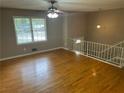 Bright living room with shining hardwood floors and white banister to upper level at 6956 Kimberland Gardens Ln, Lithonia, GA 30058
