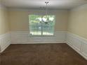 Cozy dining room with wainscoting detail, a chandelier, and a view of the green outdoors at 3827 Micah Ln, Ellenwood, GA 30294