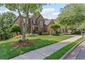 Charming two-story brick home with lush front lawn and mature trees on quiet street at 7047 Bennington Ln, Cumming, GA 30041