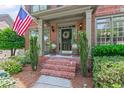 Inviting front porch with brick steps, decorative plants, and elegant front door with sidelights at 7047 Bennington Ln, Cumming, GA 30041