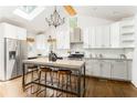 Bright kitchen features an island with seating, white cabinets, stainless steel appliances, and modern lighting at 936 Ormewood Se Ter, Atlanta, GA 30316