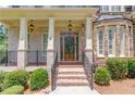 Close-up of a home's entrance with decorative wood door, stone accents, and manicured shrubs at 255 Beech Tree Holw, Sugar Hill, GA 30518