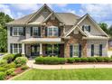 Charming home featuring brick and stone facade, lush landscaping, and a welcoming front porch at 5220 Southern Hills Ln, Cumming, GA 30040