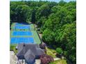 An aerial view of three tennis courts and a clubhouse in a lush wooded area at 2628 Amberly Dr, Dunwoody, GA 30360