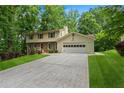 Traditional home featuring a lush green lawn, mature trees, and a two-car attached garage at 3802 Sw Knights Bridge Sw Rd, Lilburn, GA 30047