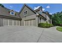 View of a three-car garage featuring modern doors and a wide driveway surrounded by mature trees at 1168 Atcheson Ln, Atlanta, GA 30338