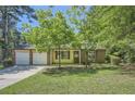 Inviting single-story home featuring a brick facade, attached two-car garage, and manicured lawn with mature trees at 2948 Sagewood Dr, Snellville, GA 30039