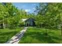 Quaint blue house with a stone walkway surrounded by mature trees and a green lawn at 13795 Arnold Mill Rd, Roswell, GA 30075