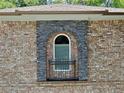 Close-up of a rounded window framed with stone detailing and a decorative railing at 4590 River Stone Trl, Douglasville, GA 30135
