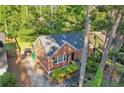 Aerial view of brick home with well-kept lawn, driveway, mature trees, and verdant surroundings at 1521 Deerwood Dr, Decatur, GA 30030