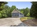 View of blue home from cracked driveway with fenced backyard area and treeline at 735 Poplar Rd, Dallas, GA 30157