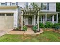 Close-up of a charming home entrance featuring a pergola, well-kept lawn, and an attached two-car garage at 119 Laurel Mill Ct, Roswell, GA 30076