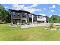 Modern home featuring black stone accents, a white facade, large windows, and a sprawling green lawn at 1336 Azalea Dr, Lawrenceville, GA 30043