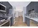 Modern kitchen with stainless steel appliances, granite countertops, mosaic backsplash, and sleek gray cabinetry at 195 14Th St # 902, Atlanta, GA 30309