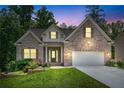Lovely brick home exterior with a well-kept lawn, two-car garage, and welcoming entrance illuminated at dusk at 350 Paces Dr, Lithia Springs, GA 30122