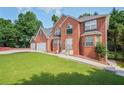 Charming two-story brick home with three car garage and large front lawn, surrounded by trees at 3524 Forest Downs Cv, Decatur, GA 30034