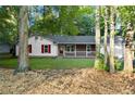 Front exterior view of home with mature trees, featuring red shutters, brick accents and an attached garage at 11006 Clearwater Dr, Hampton, GA 30228
