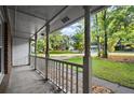 View of the white-columned porch with concrete floor looking out to the street and lush green lawn at 11006 Clearwater Dr, Hampton, GA 30228