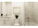 Bright bathroom featuring white cabinets, modern sink, toilet, and stylishly tiled tub at 416 Valley View Trl, Canton, GA 30115