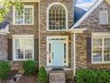 Close-up of a brick home featuring a light blue front door, classic shutters, and manicured landscaping at 4295 Cami Way, Buford, GA 30519