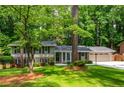 Traditional home showcasing lush green lawn, mature trees, and well-kept landscaping at 6505 Whispering Ln, Atlanta, GA 30328