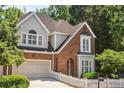Two-story brick and gray shingle home with a two-car garage, manicured lawn, and white picket fence at 2567 Briers North Dr, Dunwoody, GA 30360
