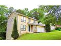Inviting two-story home with attached garage, lush green lawn, and mature trees in a peaceful setting at 1012 Chapman Cir, Stone Mountain, GA 30088