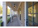 Inviting covered front porch with brick flooring, decorative columns, and stylish pendant lighting fixtures at 157 Basil St, Cumming, GA 30040