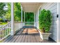 Inviting covered front porch with a dark stained floor, a neutral rug, and a potted evergreen at 940 Longley Nw Ave, Atlanta, GA 30318