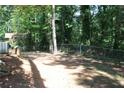 Fenced backyard featuring a mix of dirt and tree cover with mature trees at 5561 Petite Pt, Lithonia, GA 30058