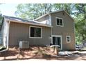 Back exterior view displaying siding, windows, patio, and A/C unit in a wooded yard at 5561 Petite Pt, Lithonia, GA 30058