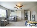 Cozy bedroom with plush carpet, soft gray walls, ceiling fan, and a comfortable seating area at 3589 Tamerton Trce, Buford, GA 30519