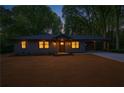 Twilight view of gray home featuring a covered carport and professionally landscaped front yard, illuminated windows at 1995 Mcafee Rd, Decatur, GA 30032