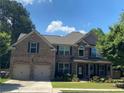 Charming two-story brick home featuring an attached two-car garage, covered porch and lush landscaping at 200 Birchwood Dr, Loganville, GA 30052