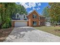 Classic two-story brick home with a two-car garage, dormers, a traditional facade, and mature shade trees at 4999 Willow Creek Dr, Woodstock, GA 30188