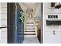 Inviting entryway with white tile and wood stairs, featuring an open door, mail slot, and wreath at 1027 Riverbend Club Se Dr, Atlanta, GA 30339