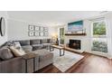 Bright living room with a cozy fireplace, hardwood floors, and a comfortable grey sectional sofa at 1027 Riverbend Club Se Dr, Atlanta, GA 30339