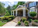 Inviting front porch with stone steps, white columns, wrought iron railing, and lush landscaping at 2101 Hunters Green Dr, Lawrenceville, GA 30043