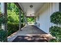 Covered side porch with brick flooring, offering a serene outdoor seating area surrounded by greenery at 290 Dania Dr, Alpharetta, GA 30009